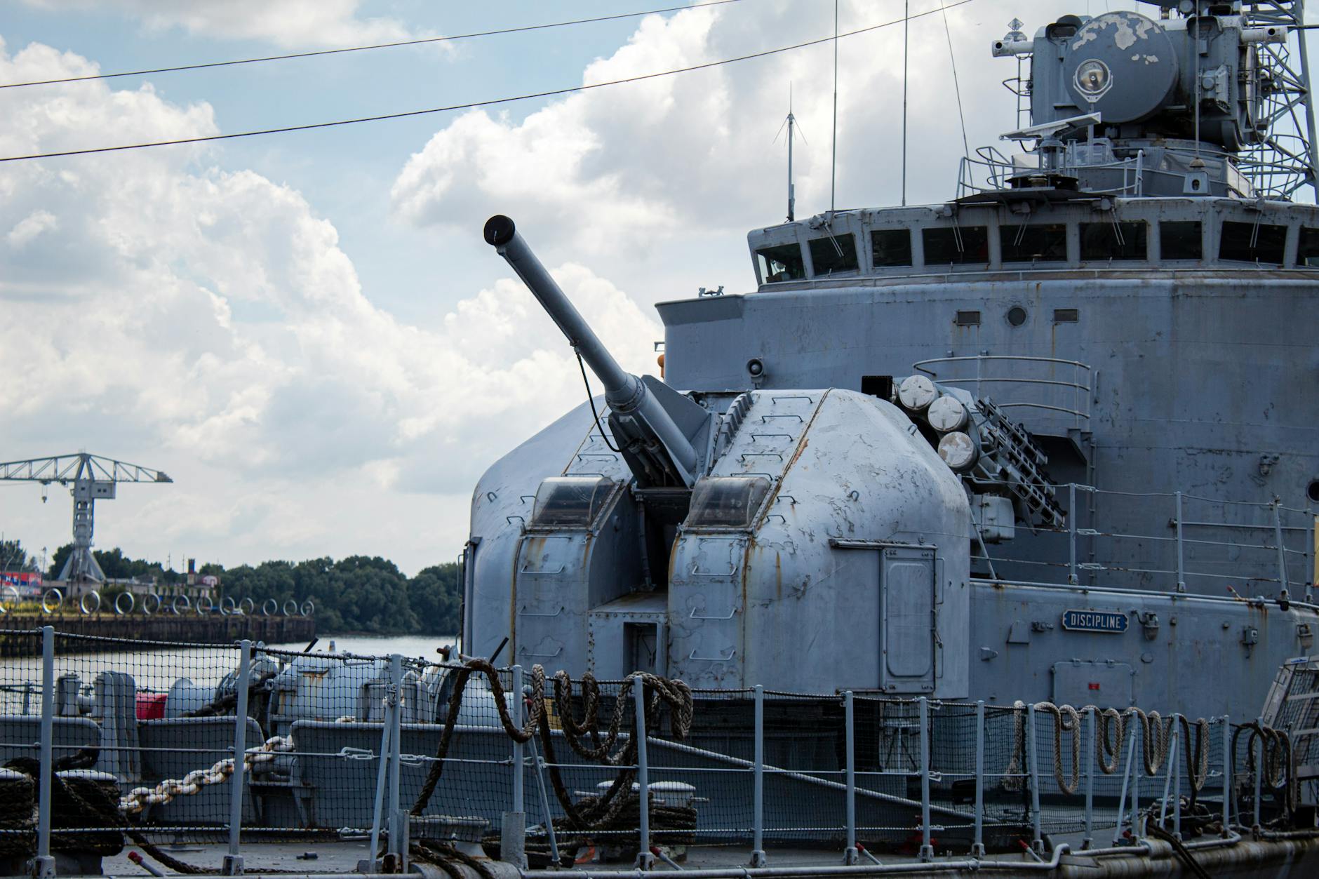 Naval warship cannon on deck at a harbor